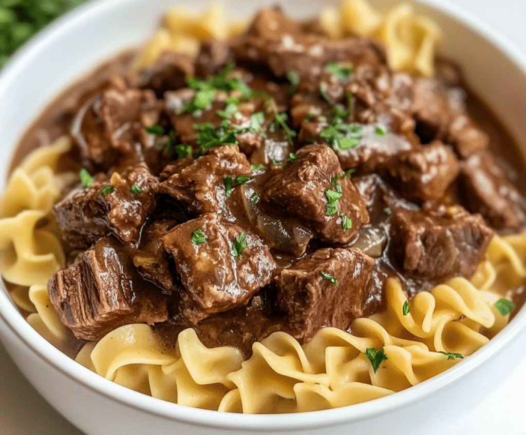 Crockpot Beef Tips and Noodles served in a white slow cooker with steam